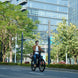 Man riding a Freego City Flow A1 Electric Bike on a city street with modern buildings and trees in the background