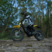 Rider on Freego Nova 5 electric dirt bike speeding through a forest trail.