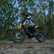 Rider on Freego Nova 5 electric dirt bike speeding through a forest trail.