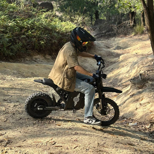 Rider on Freego X0 electric mini dirt bike navigating a wooded dirt trail.