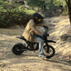 Rider on Freego X0 electric mini dirt bike navigating a wooded dirt trail.
