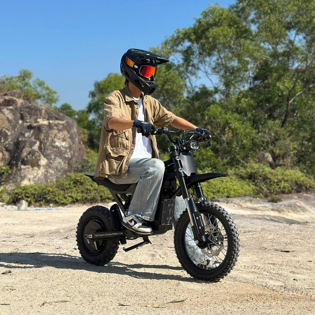 Teen rider on Freego X0 electric mini bike navigating rocky terrain with off-road tires and forest backdrop